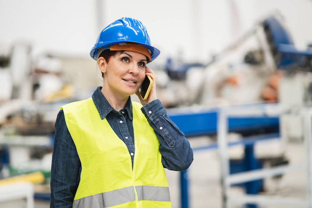 kypsä nainen insinööri tehtaalla, puhuu matkapuhelimella - Valokuva, kuva
