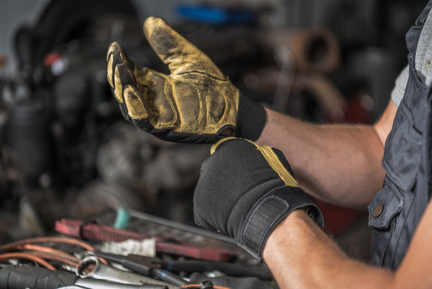 Closeup of the Caucasian Mechanic 's Dirty Work Gloves After a Day of Hard Work at the Car Shop Station. Motiv automobilového průmyslu. - Fotografie, Obrázek