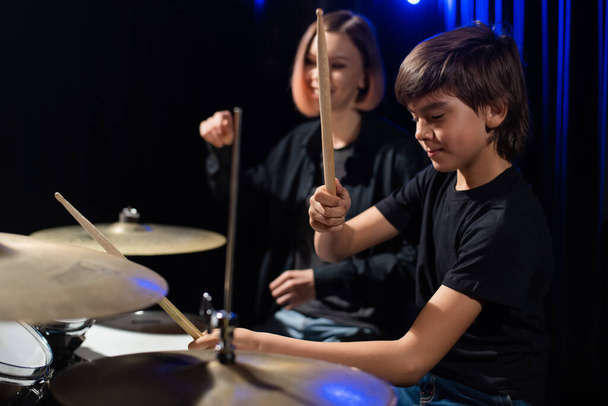 Молода жінка навчає хлопчика грати на барабанах
 - Фото, зображення