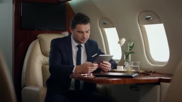 Nervous manager holding tablet computer on luxury jet. Focused man looking pad screen checking company reports. Puzzled successful businessman touch digital computer. Ceo solving problem on airplane - Footage, Video