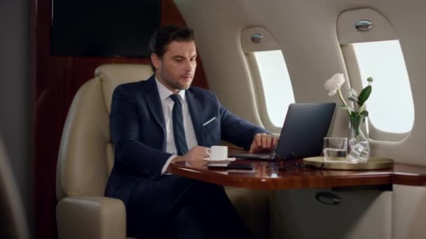 laptop de trabalho profissional estressado no avião. Um homem concentrado a tomar café na cabana da classe executiva. Profissional olhar tela do computador digitando web de navegação. Frustrado ceo verificando relatórios on-line - Filmagem, Vídeo