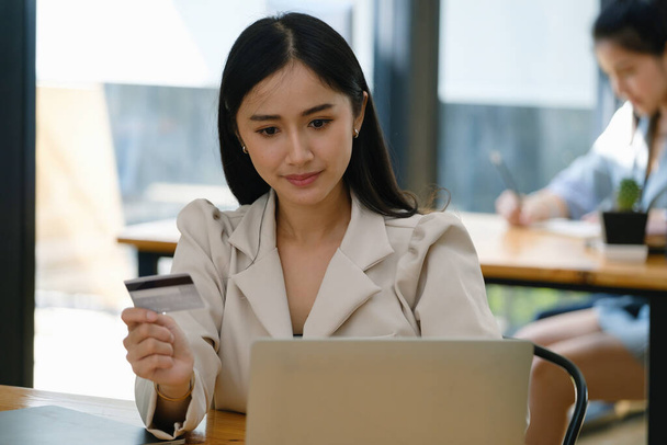 Онлайн-шопінги та інтернет-платежі, красиві азіатські жінки використовують свої кредитні картки та комп'ютерний ноутбук, щоб придбати онлайн або проводити доручення в цифровому світі.. - Фото, зображення