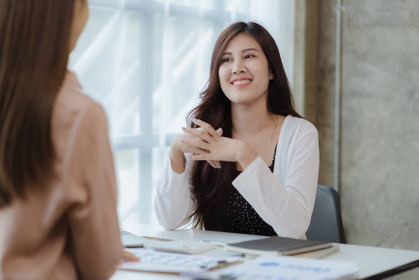 Két gyönyörű ázsiai nő találkozik egy céges tárgyalóban, hogy megvitassák az üzleti terv fejlesztésére és az üzleti terv követésére irányuló terveket. Üzleti megbeszélés ötlete. - Fotó, kép