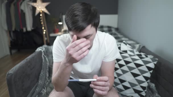 Worried man looks at pregnancy test at home. Husband upset about pregnancy test results. Male upset about his wife negative pregnancy test. Im not going to be daddy again. Im too young to be father - Footage, Video