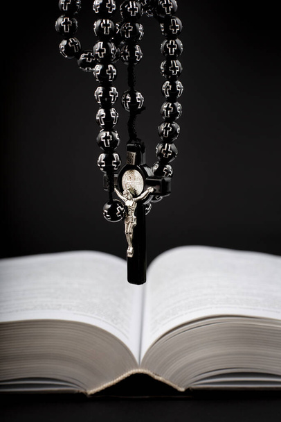 Traditional christian holy religious wooden rosary with bible on black background - Foto, Bild