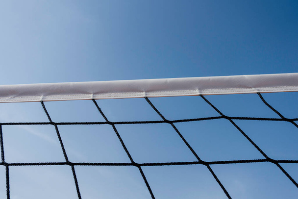 Тенісна або волейбольна сітка на тлі чистого блакитного неба. Спортивне поле на свіжому повітрі в сонячний день
. - Фото, зображення