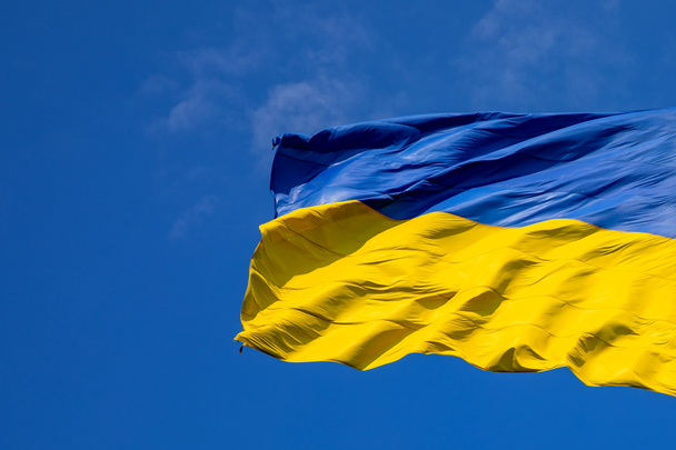 Прапор України на тлі синього неба. Найбільший прапор України. - Фото, зображення
