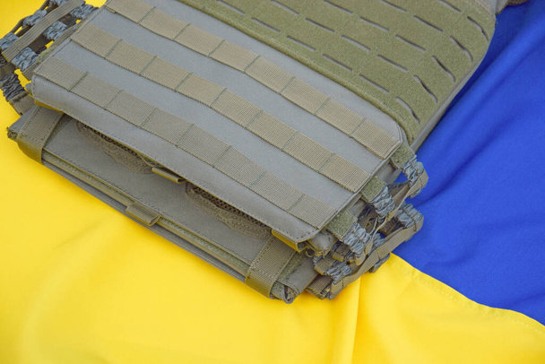 Тактические, военные бронежилеты с номерами на фоне флага Украины. Концепция защиты организма от выстрелов в войне на Украине. - Фото, изображение