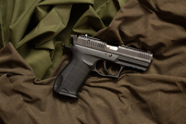 Die Waffe liegt auf einem zerknitterten grünen Tuch in Großaufnahme, Waffe - Foto, Bild