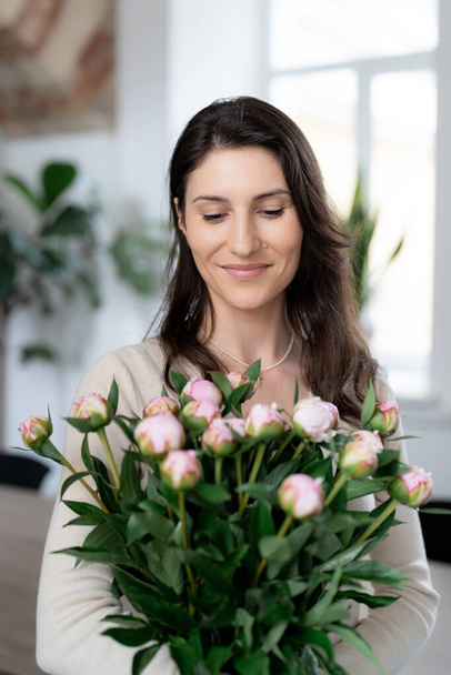 Donna positiva che tiene un enorme mazzo di fiori nel suo ufficio. Regalo di compleanno sorriso. - Foto, immagini