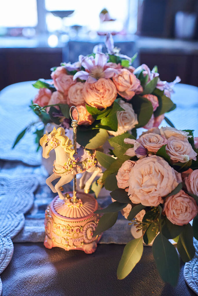 une boîte à musique avec un cheval parmi les bouquets de fleurs sur la table, plan rapproché - Photo, image