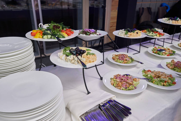 Ein gedeckter Tisch mit frischen Salaten in Tellern bei einem Bankett wartet auf seine Gäste - Foto, Bild