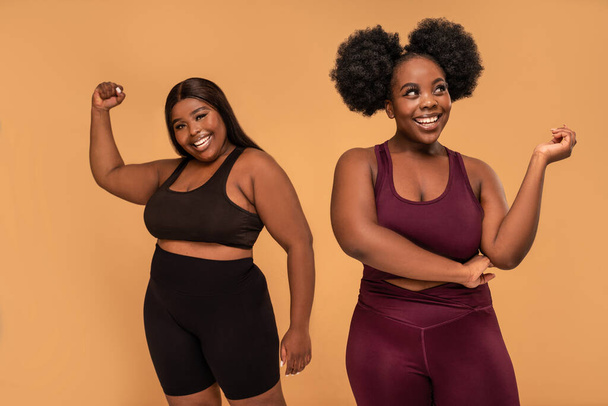 Active two plus size women after training in fashionable sporty clothes posing together, smiling. Real people lifestyle. Gym, healthy lifestyle concept. Body acceptance. - 写真・画像