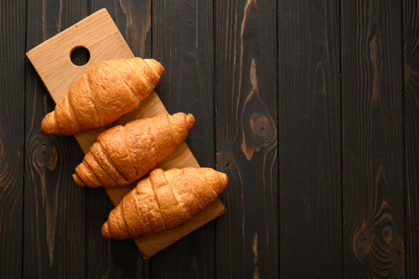 čerstvé croissanty na dřevěném pozadí. - Fotografie, Obrázek