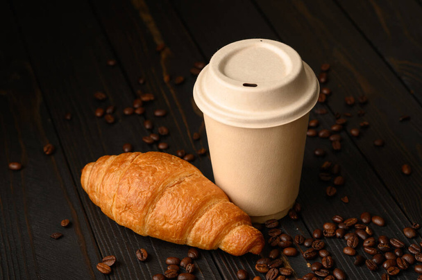 Croissants with coffee in a disposable glass on a wooden background. - Photo, Image