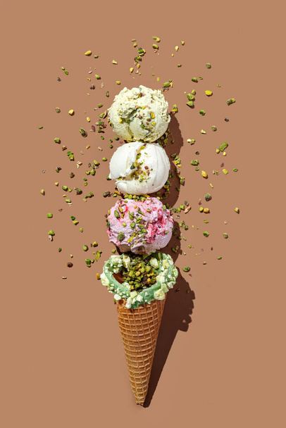 Waffeleis-Tüte mit Eiskugeln Pistazien, Himbeeren, Vanille und Banane, isoliert auf braunem Hintergrund. Kontinuierliches Muster. Draufsicht, hartes Licht - Foto, Bild