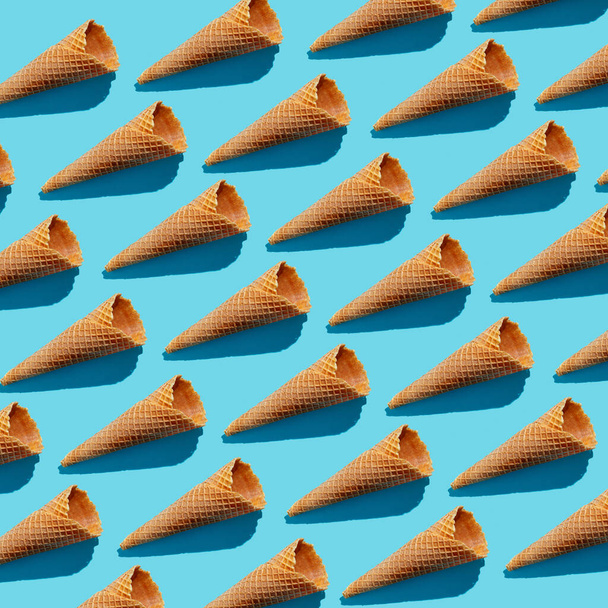 Пустые вафли мороженое конусы непрерывный узор на голубом фоне, жесткий свет - Фото, изображение