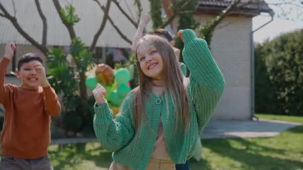 Kinder haben Spaß beim Tanzen auf einer Hinterhof-Geburtstagsparty an einem sonnigen Tag. Geburtstagsparty im Grünen. Jungen und Mädchen tanzen und drehen an einem sonnigen Tag draußen. Hochwertiges 4k Filmmaterial - Filmmaterial, Video