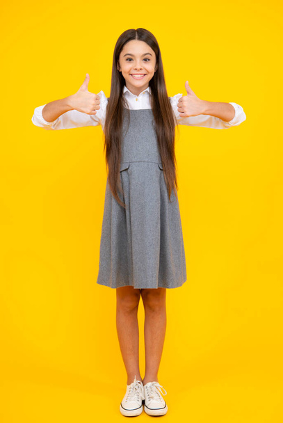Подобається. Портрет радісної дівчинки-підлітка, що показує великі пальці вгору і посміхається, жовтий фон з копією простору
 - Фото, зображення