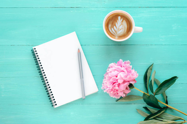 Blank notepad with pencil, coffee cup and peony flower on turquoise blue table. Festive background. Top view, flat lay, mockup. - Zdjęcie, obraz