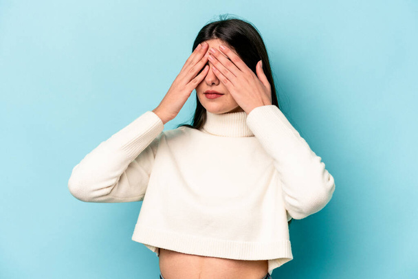 Young caucasian woman isolated on blue background afraid covering eyes with hands. - Fotoğraf, Görsel