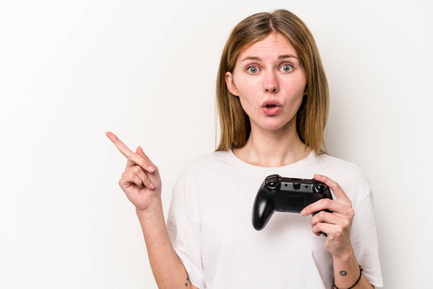 Young English woman playing with a video game controller isolated white background pointing to the side - Foto, Imagen
