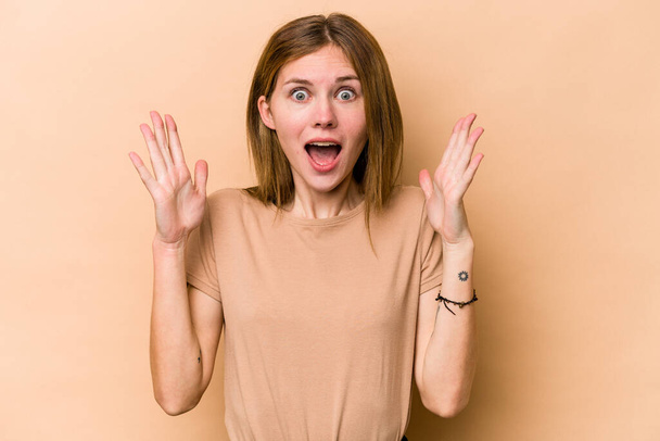 Young English woman isolated on beige background celebrating a victory or success, he is surprised and shocked. - Foto, imagen