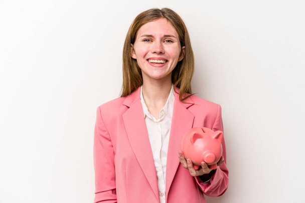 Fiatal üzleti angol nő kezében egy piggybank elszigetelt fehér háttér boldog, mosolygós és vidám. - Fotó, kép