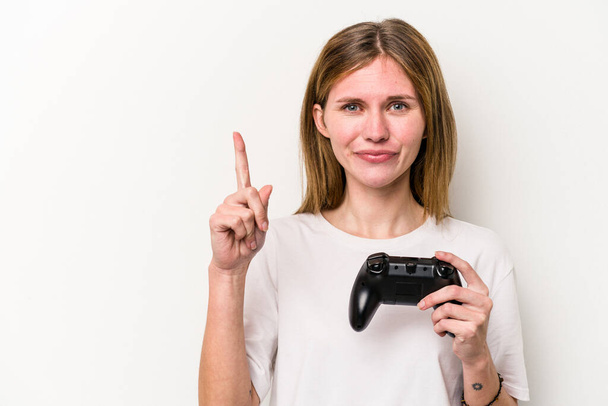 Young English woman playing with a video game controller isolated white background showing number one with finger. - Foto, Bild