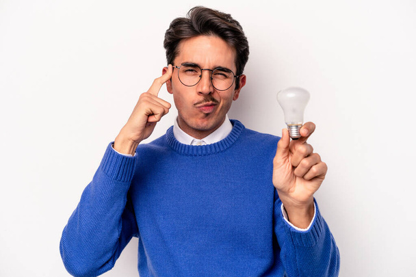 Young caucasian man holding a lightbulb isolated on white background - Fotografie, Obrázek