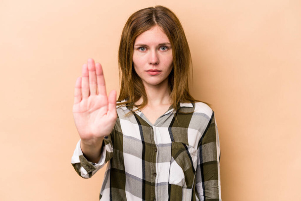 Young English woman isolated on beige background standing with outstretched hand showing stop sign, preventing you. - Photo, Image