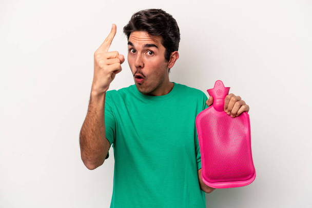 Young caucasian man holding a water bag isolated on white background having an idea, inspiration concept. - Photo, Image