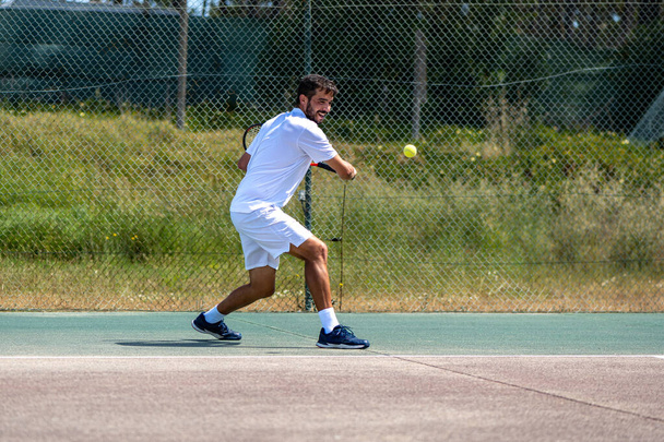 Jugador de tenis realizando un lanzamiento en la cancha. - Foto, Imagen
