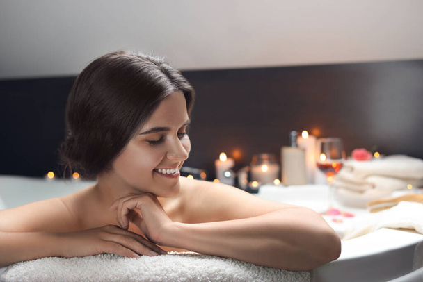 Happy beautiful woman taking bath indoors. Romantic atmosphere - Foto, Bild