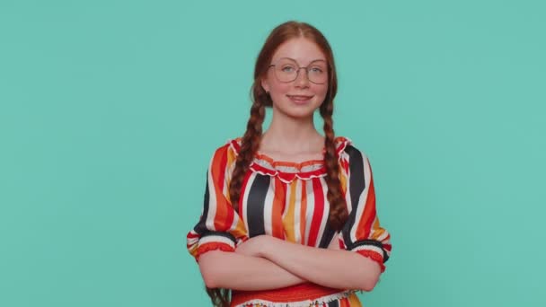 Smiling playful happy redhead girl blinking eye, looking at camera with toothy smile, winking and flirting, expressing optimism. Young one teenager ginger child kid isolated on blue studio background - Footage, Video