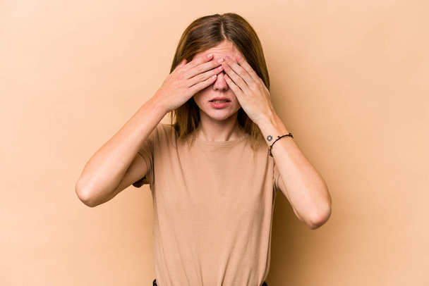 Fiatal angol nő elszigetelt bézs háttér félelem eltakaró szem kezével. - Fotó, kép