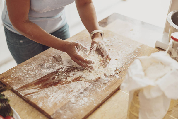 Το να πλέκεις τη ζύμη της πίτσας με το χέρι στον πίνακα της κουζίνας είναι το κλειδί για την ποιότητα της σπιτικής πίτσας - Φωτογραφία, εικόνα
