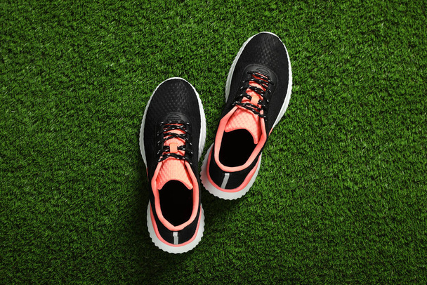 Pair of stylish sport shoes on green grass, flat lay - Foto, Bild
