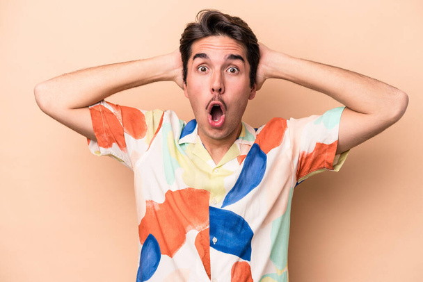 Young caucasian man isolated on beige background surprised and shocked. - Foto, Imagem