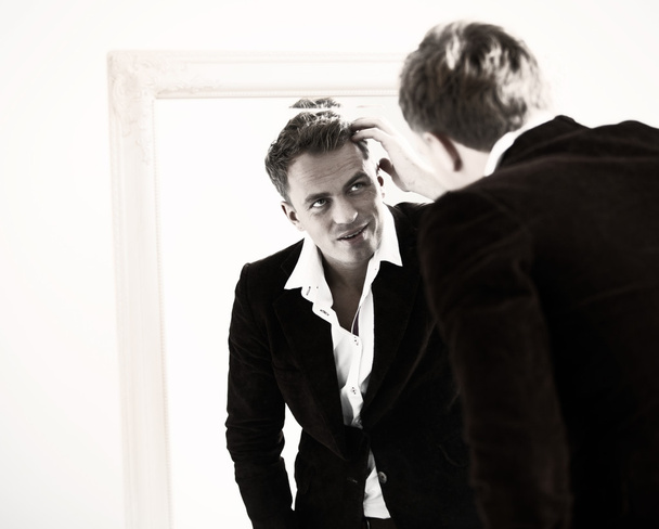Stylish sexy man checking his hairstyle in mirror - Photo, image