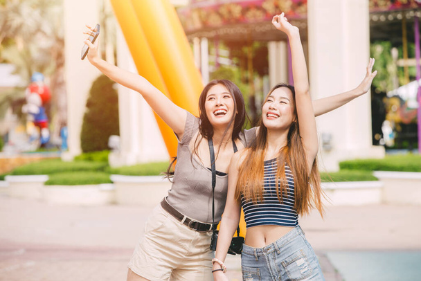 Duas mulheres asiáticas relaxar casual feliz sorrindo desfrutar no parque de diversões ao ar livre. - Foto, Imagem