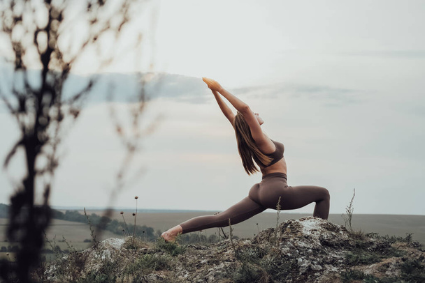 Sporty Girl Doing Stretching Exercises on Top of Hill, Young Woman Practice Yoga Outdoors at Sunset - Fotoğraf, Görsel