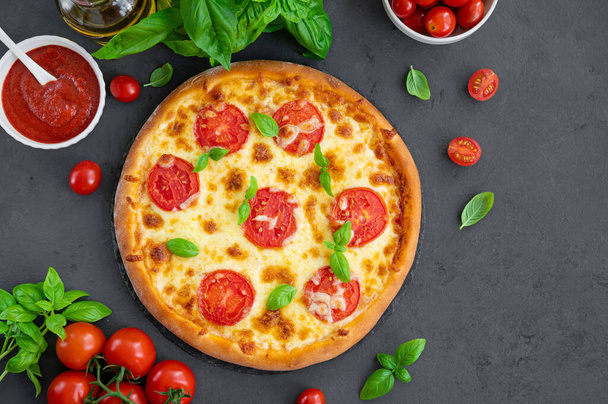 Geleneksel İtalyan pizzası Margarita ya da domates soslu margharita, mozzarella peyniri ve gri arka planda taze yeşil fesleğen. Üst görünüm, alanı kopyala - Fotoğraf, Görsel