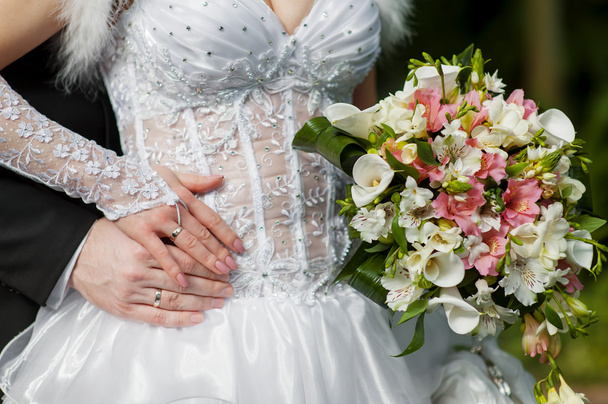 anéis noiva e noivo no fundo de um buquê de casamento
 - Foto, Imagem