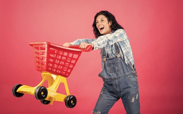 Nice purchase. Female housewife with shopping trolley in supermarket. girl pushing shopping cart in the mall. happy woman carry shopping cart. shopper girl have fun. marketing concept. - Foto, Imagem