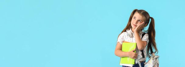Schattig klein schoolmeisje op lichtblauwe achtergrond met ruimte voor tekst - Foto, afbeelding