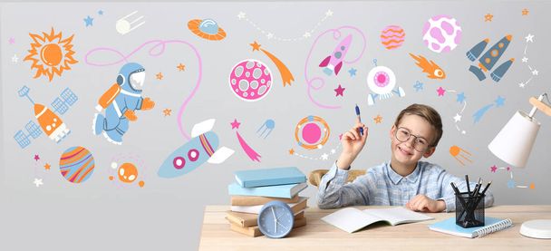 Pieni koulupoika tekee läksyjä kevyellä taustalla piirretyn tilan kanssa - Valokuva, kuva