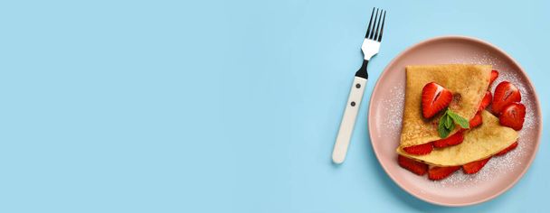 Plate of thin pancakes with strawberry and fork on blue background with space for text - Foto, immagini