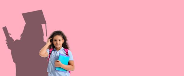 Schattig Afrikaans-Amerikaans schoolmeisje dromen over hoger onderwijs op roze achtergrond met ruimte voor tekst - Foto, afbeelding