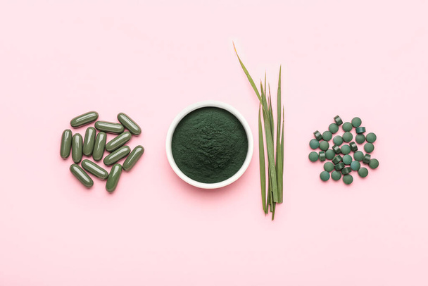 Bowl of spirulina powder, leaves and pills on pink background - Photo, Image